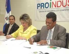 La directora de Proindustria, Alexandra Izquierdo y el alcalde municipal de Los Alcarrizos, Junior Santos, firman el acuerdo.