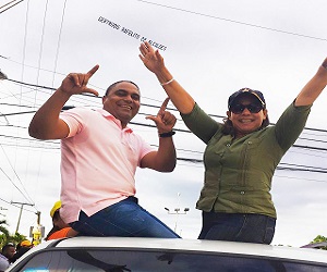 La diputada Gertrudis junto con Rafelito 22 durante una actividad. En el fondo y arriba, se puede observar el letrero que llevaba la avioneta.